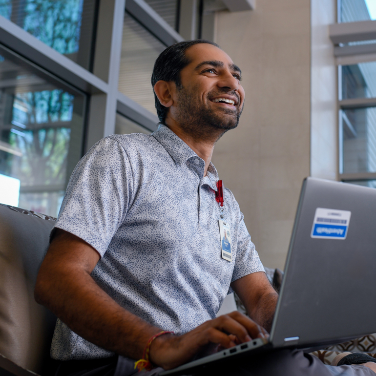A smiling male information technology professional working at a computer