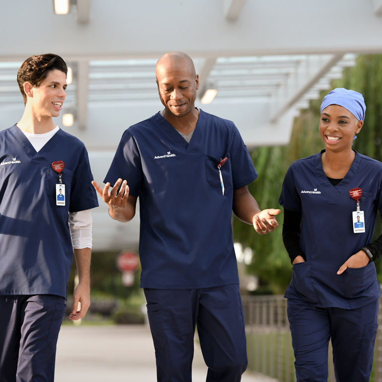 Three smiling nursing professionals walking and talking together outside