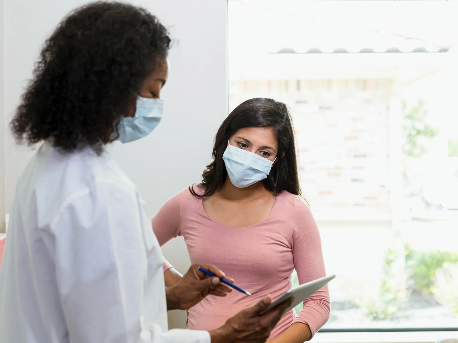 Female doctor goes over a medical chart with a female patient.