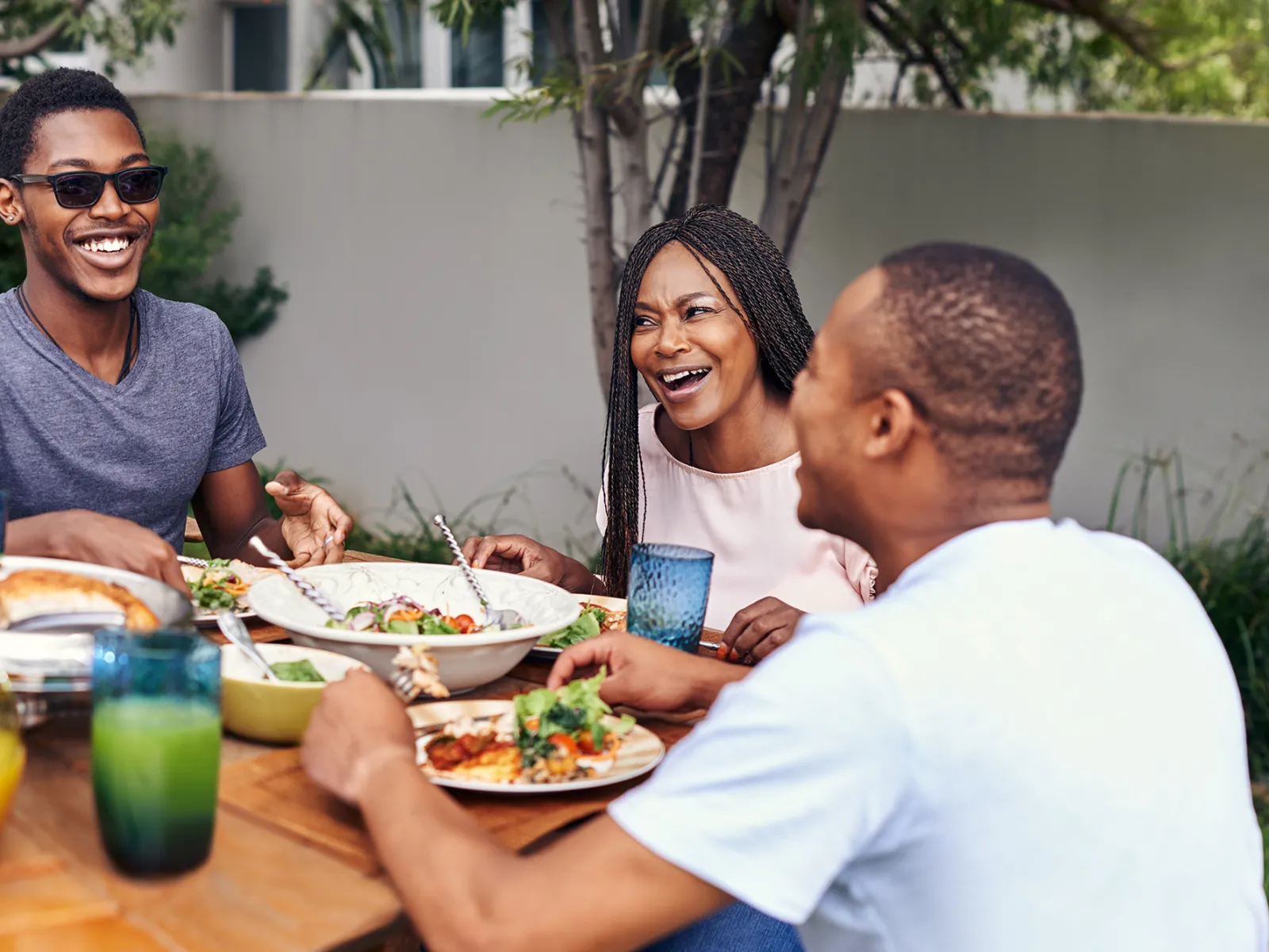 A Family Gathers Around a Outdoor Table to Enjoy a Meal.