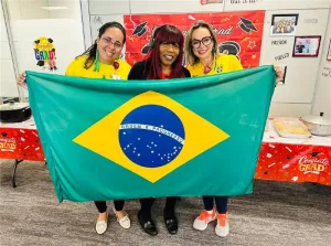 Linda Casimir (middle) with two team members holding a Brazilian flag