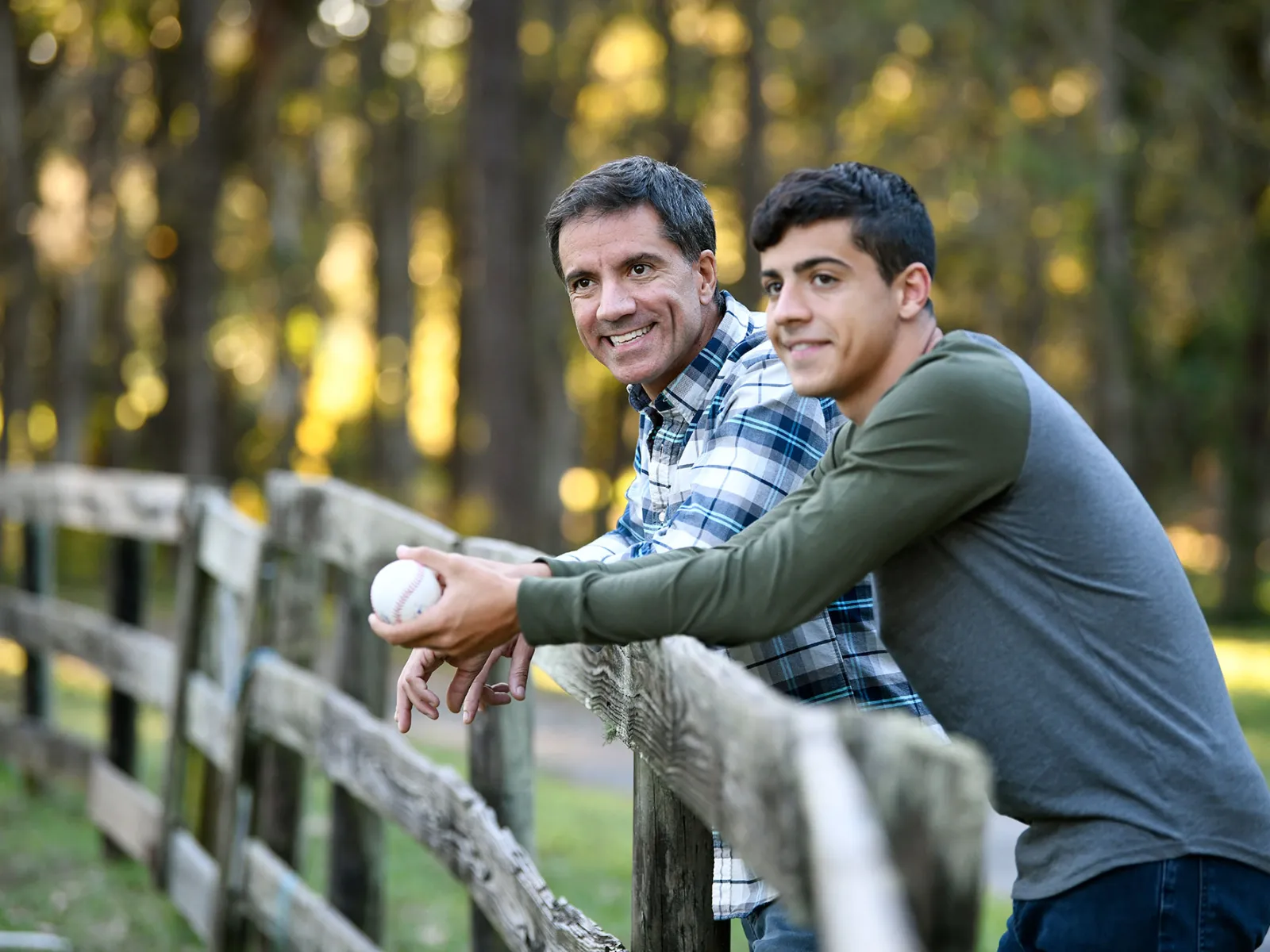 A father and son leaning forward on a fence