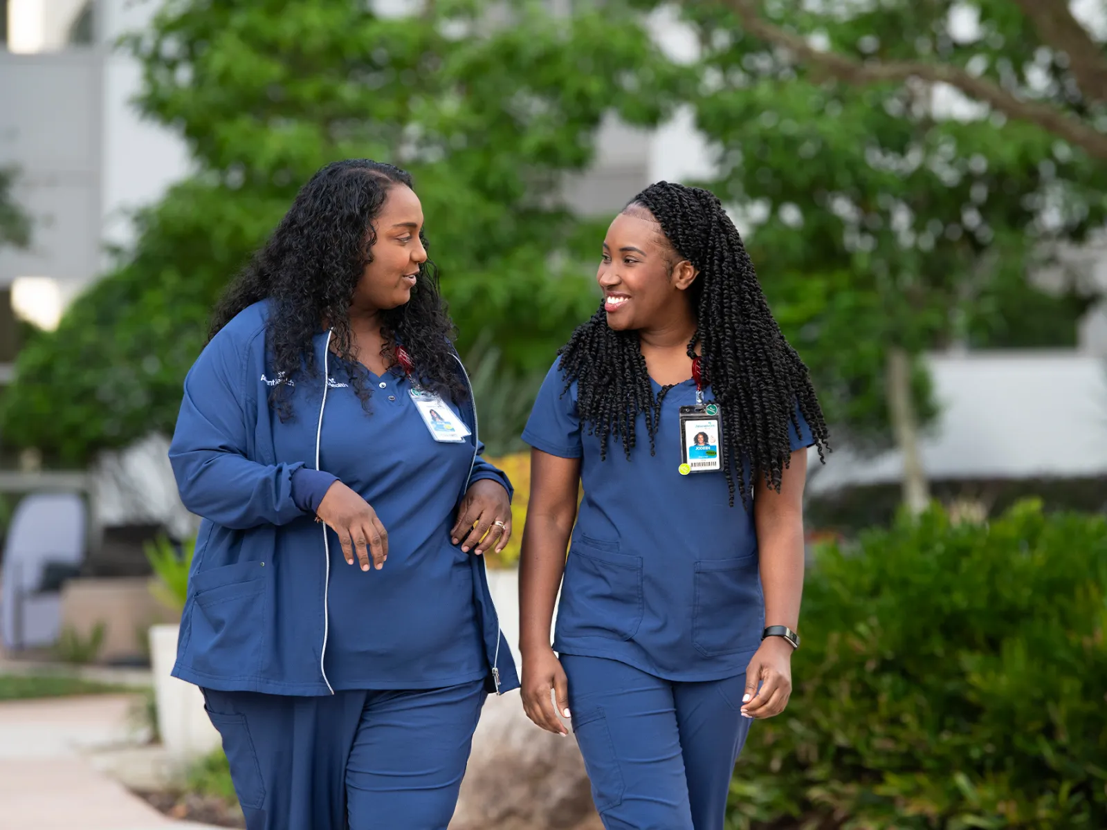Two nurses walking outdoors and talking together.
