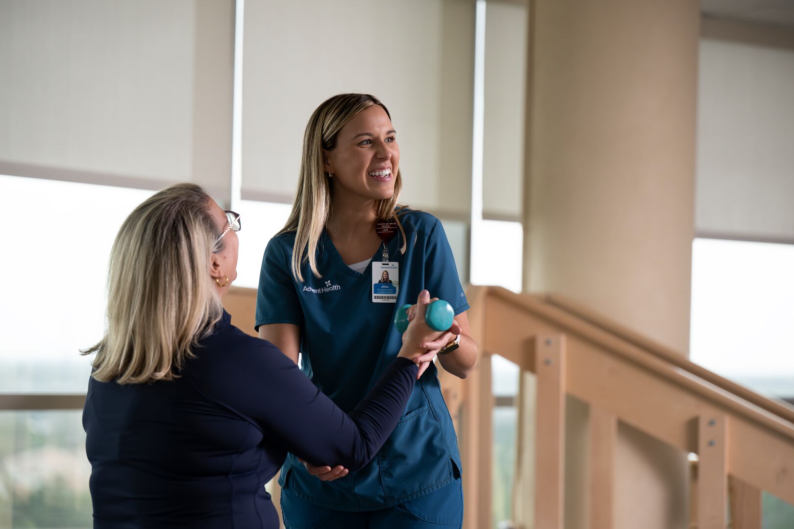AdventHealth clinician assisting a patient with a light hand exercise during a rehabilitation session.