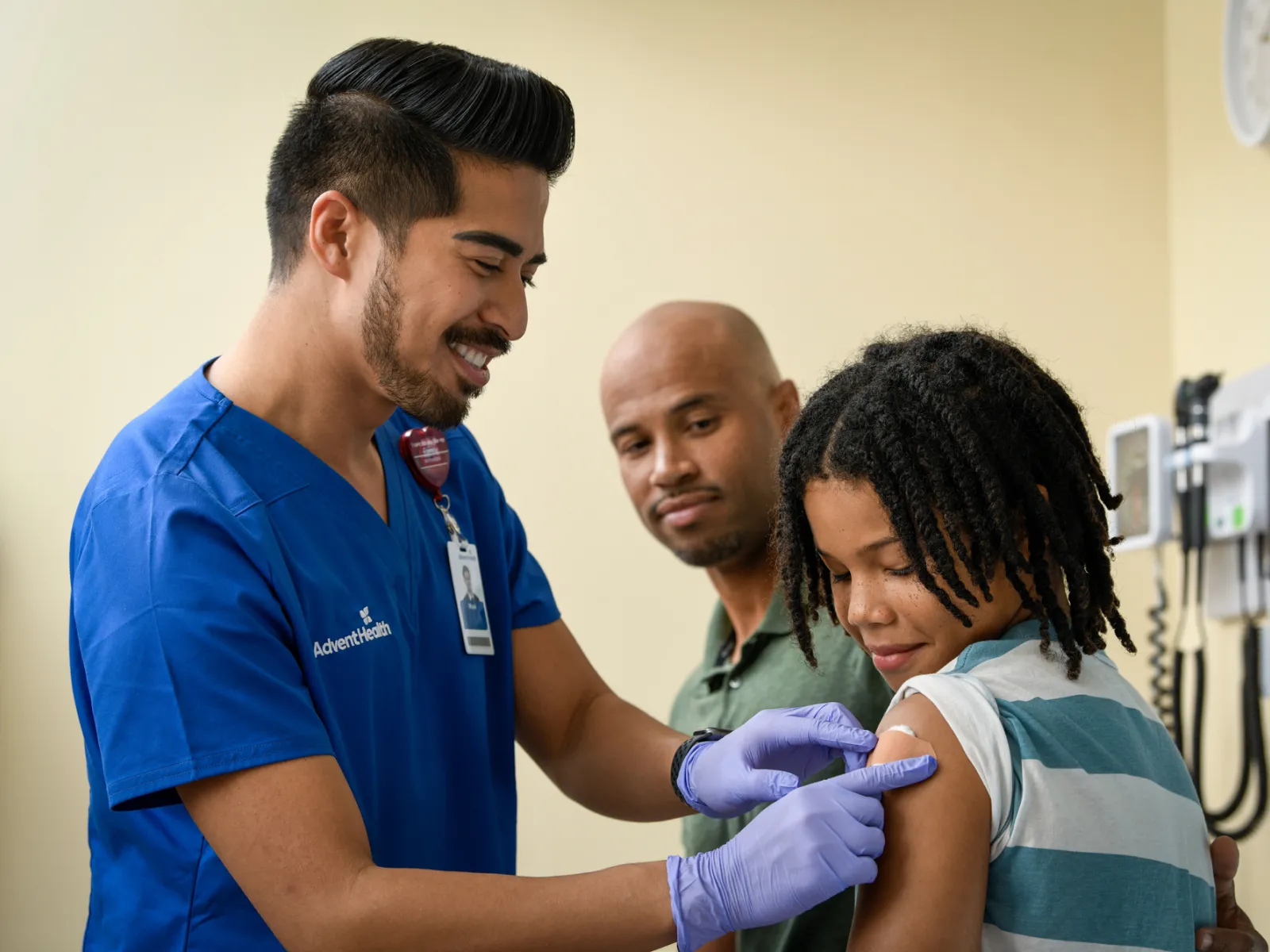 AdventHealth clinician administering a vaccine to a child while a parent looks on in a medical exam room.