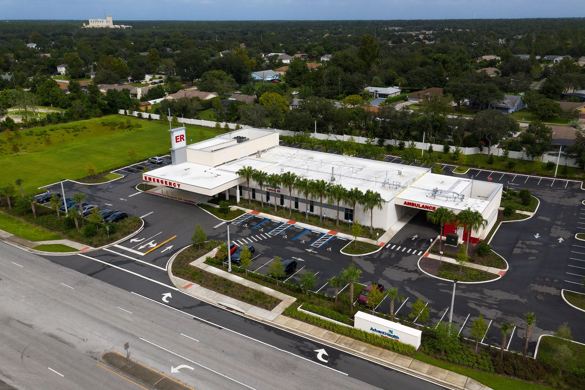 Aerial view of the AdventHealth Deltona emergency department, showing the ER entrance, ambulance bay, parking areas, and surrounding neighborhood.