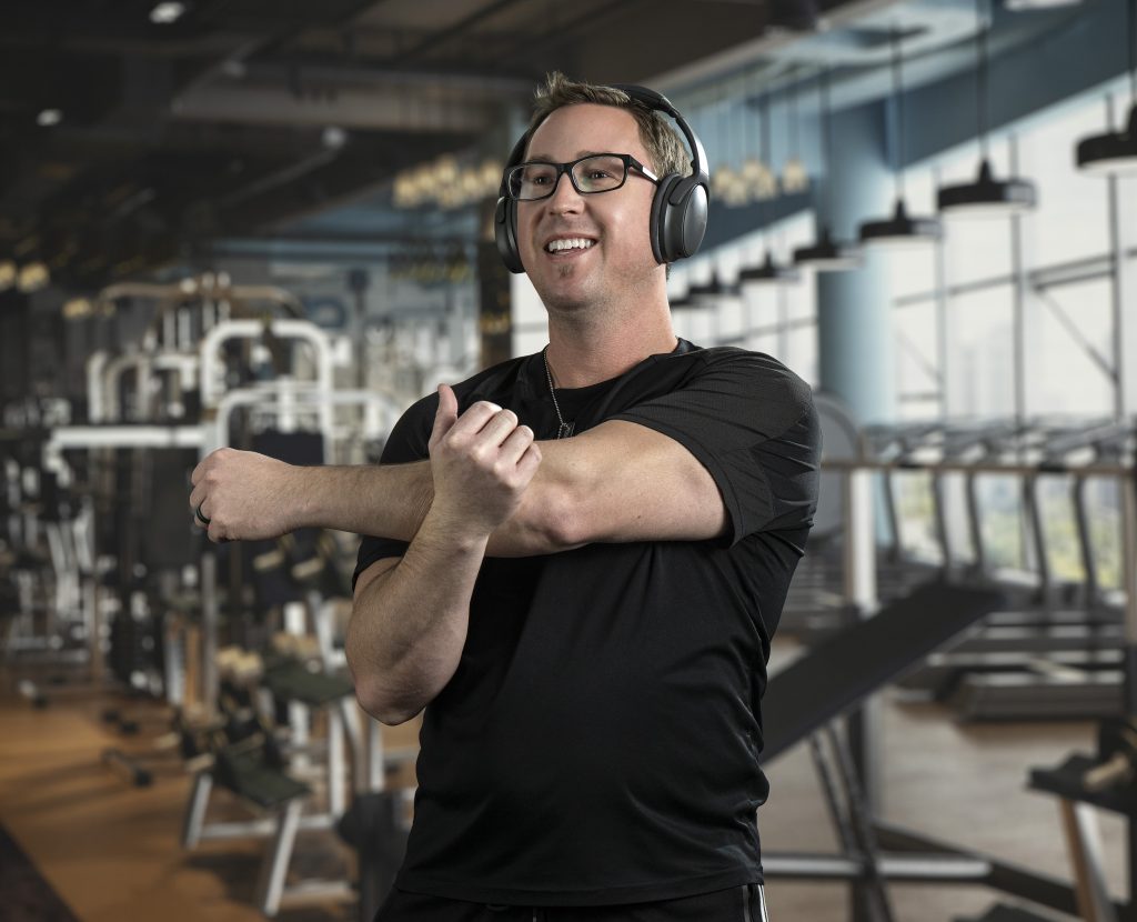 A smiling man stretching in a gym