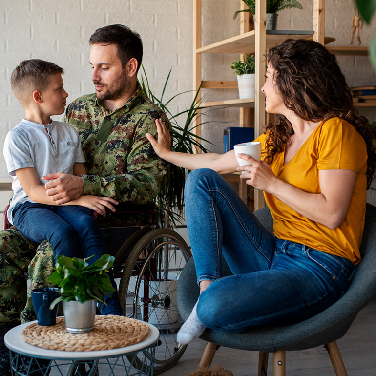Military veteran in uniform at home with family, seated in a wheelchair.