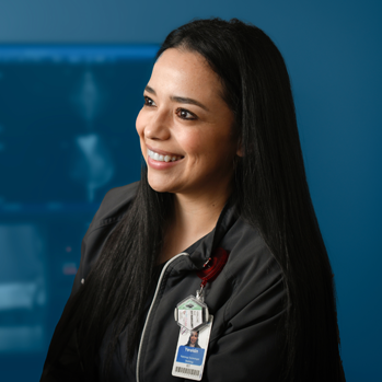 A smiling female radiology technologist in an imaging setting